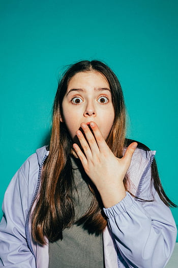 chockad tjej, ung tjej, hand på munnen, kricka bakgrund, förvånad uttryck, emotionell reaktion, studio porträtt, vardaglig klädsel, inomhusfotografering, kvinnlig ämne, uttryckligt ansikte