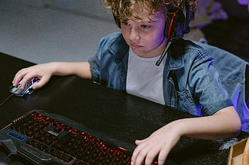 boy, headphones, computer keyboard, mouse, playing game, indoor, young child, gaming, computer game, indoor activity, focused
