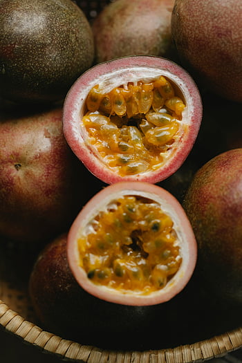 ripe passion fruits, wicker bowl, sliced passion fruit, vibrant pulp, seeds, healthy eating, close-up view, fresh fruit, exotic fruit, tropical fruit, passion fruit pulp