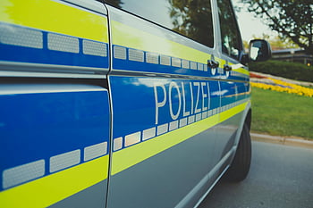 German police car, Polizei, close-up, parked outdoors, sunny day, police vehicle, blue and yellow, emergency vehicle, law enforcement, public safety, street scene