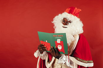 African American Santa Claus, reading Christmas card, festive spirit, red backdrop, holiday season, Christmas celebration, Santa Claus costume, Christmas card reading, festive atmosphere, holiday cheer, African American Santa
