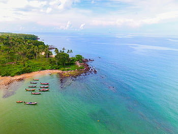 aerial view, ocean, tropical beach, docked boats, lush greenery, coastline, serene, bird's eye view, tropical, sea, boats