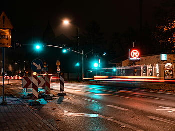 nighttime city intersection, blue traffic light, illuminated street signs, traffic, night scene, urban scene, street signs, traffic signals, city lights, long exposure, road construction