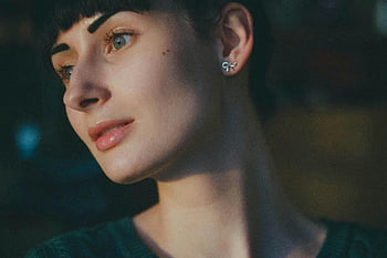 žena, stříbrné náušnice, zelené tričko, detailní portrét, Promyšlená mladá žena, krátké vlasy, matné osvětlení, náušnice, zamyšlený výraz, Mladá žena, portrétní fotografie