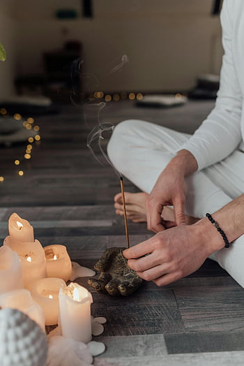 holding incense, peaceful meditation, candles, tranquil atmosphere, indoor scene, meditation scene, incense smoke, meditative atmosphere, relaxation, spiritual practice, candlelight ambiance