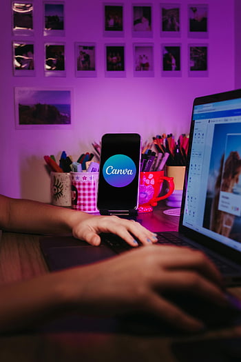 Canva logo, phone on stand, laptop on desk, creative workspace, vibrant desk setup, organized desk, smartphone displaying Canva, home workspace, desk setup, Canva app, laptop and smartphone