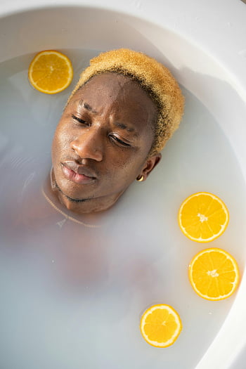 Afroamerikanermann, Badewanne, Orangenscheiben, Serene Bad, entspannend, junger Mann, Wasser, Badszene, Orangenscheiben in Wasser, Entspannung, Badezeit