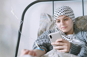 paciente usando el teléfono, tratamiento de quimioterapia, cuarto de hospital, mujer joven, fuerza y ​​esperanza, tratamiento médico, enfermo de cáncer, teléfono durante el tratamiento, Cama de hospital, cuidado de la salud, viaje de recuperación
