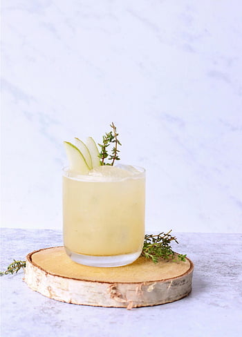 pear mocktail, thyme garnish, cold cocktail, summer refreshment, wooden slice, ice cubes, pear slices, glass drink, refreshing beverage, mocktail drink, thyme mocktail