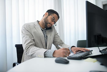 Giacca da uomo in abito beige, seduto al tavolo, computer, uomo d'affari focalizzato, multitasking, Telefono, scrittura, scrivania da ufficio, uomo d'affari multitasking, lavoro d'ufficio, multitasking professionale