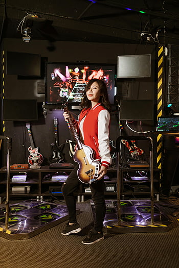 guitar controller, young woman, Guitar Hero, vibrant gaming room, gaming room, video game, music game, arcade game, entertainment, fun, enjoyment