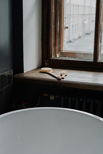 brown wooden framed glass window, minimalistic bathroom, wooden windowsill, bath brushes, relaxing routine, bathroom setup, wooden frame, glass window, bathroom decor, bath accessories, relaxing bath
