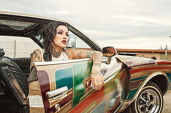 tätowierte Frau, weißes Trägershirt, klassisches Auto, mehrfarbiger Auto, Vintage Lowrider, einzigartiger Stil, Automobildesign, farbenfroher Jahrgang, Lowrider Car, Klassisches mehrfarbiges Auto, tätowierter Stil