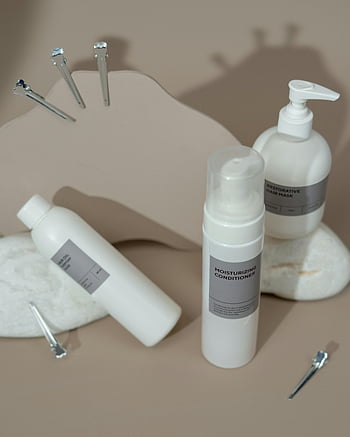 Condizionatore idratante, prodotti per la cura della pelle, sfondo neutro, luci soffuse, display minimalista, maschera per capelli, olio per capelli, bottiglie bianche, cura dei capelli, prodotti di bellezza, accessori per capelli