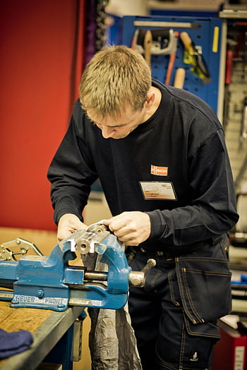 man, black top, bench vise, workshop, precision tools, equipment, crafting metal, focused, multi-word terms, SEO keywords, relevant photo