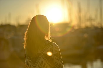 woman, standing, facing sun, sunset, silhouette, long hair, outdoor, lens flare, golden hour, peaceful, contemplative