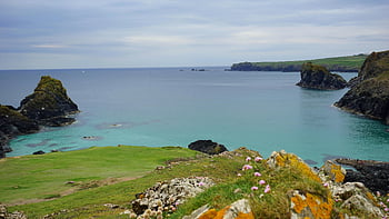 cliff, grass, body of water, seaside landscape, rocky shores, calm blue waters, cloudy sky, peaceful scenery, coastal view, natural beauty, ocean view