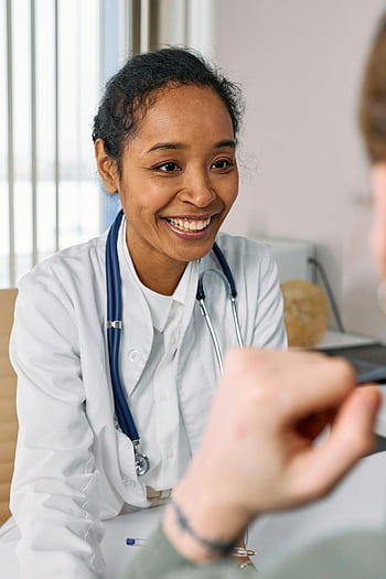Doktor se usmívá, bílý plášť, stetoskop, Vřelá konzultace, Lékař, zdravotnický pracovník, interakce s pacientem, ordinaci, Přátelský lékař, Konzultace se zdravotní péčí, Profesionální konzultace