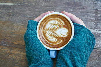 cappuccino, latte, vaahto-art, ruskea villapaita, puinen pöytä, lohduttava laukaus, kahvimuki, kädet, joilla on muki, kuuma juoma, kodikas juoma, kahvitaide
