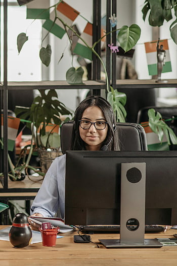 asiatisk kvinde, briller, headset, moderne kontor, skrivebord, planter, smilende, professionel, arbejdsområde, computer, indendørs