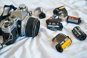 Černá a stříbrná kamera, Klasická filmová kamera, Různé filmové role, retro fotografie, vinobraní fotoaparát, filmové fotografie, 35mm film, kamerové čočky, fotografické vybavení, analogové kamery, filmové role