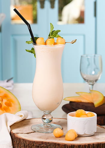 meloen milkshake, Helder glas, gesneden fruit, muntgarnering, zomerdrankje, verfrissende drank, meloen plakjes, Milkshake -glas, koel drankje, fruit garnituur, zwart rietje