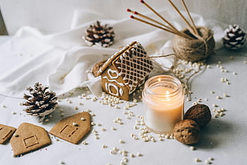 gingerbread house, lit candle, warm scene, pine cones, walnuts, festive decoration, holiday setting, cozy atmosphere, winter theme, candlelight, gingerbread pieces