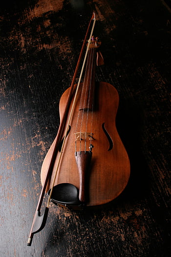 brown wooden violin, violin bow, dark wooden surface, classic mood, artistic mood, beautifully crafted violin, musical instrument, string instrument, violin photography, violin art, violin design