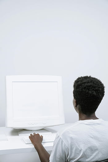 man using computer, blank screen, back view, typing, desktop computer, minimalist office, white-toned setting, person working, computer monitor, office environment, workspace