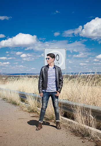 giacca di pelle nera, jeans neri, occhiali da sole neri, Uomo alla moda, Autostrada rurale, giorno soleggiato, posa sicura, segno del limite di velocità, moda all'aperto, Stile casual, cielo blu