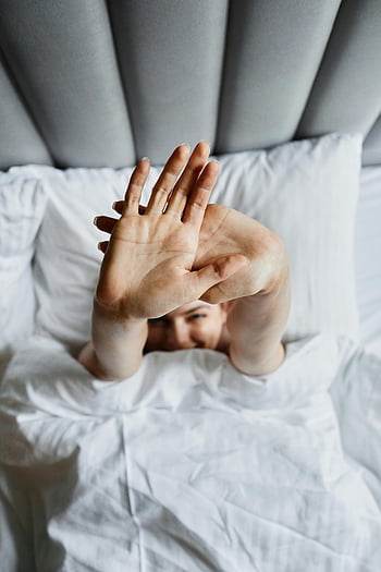 donna a letto, coperta bianca, cuscini morbidi, Atmosfera accogliente, Allungate le braccia, sdraiarsi, letto comodo, la routine del mattino, donna rilassata, Scena della camera da letto, biancheria da letto bianca