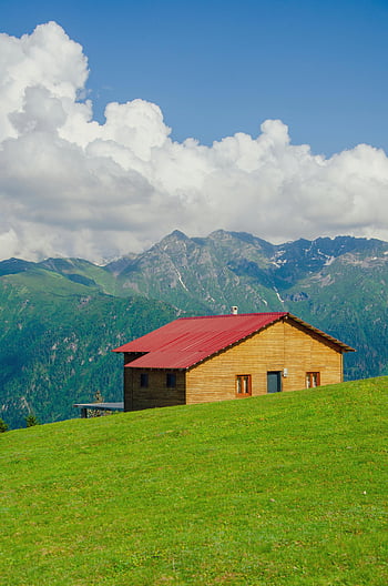 wooden house, red roof, green hillside, mountains backdrop, charming cabin, wooden cabin, hilltop house, scenic landscape, mountain view, rural setting, nature retreat