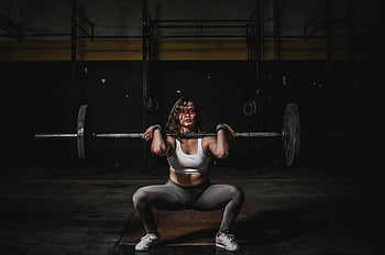 woman lifting barbell, strong female weightlifter, squatting with barbell, dimly lit gym, power and fitness, weightlifting, gym workout, fitness woman, barbell exercise, strength training, female athlete
