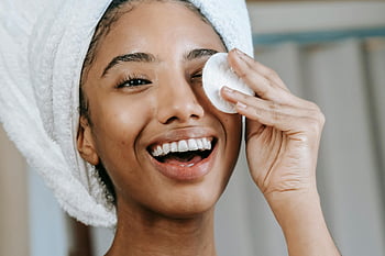 donna etnica, donna sorridente, pad di cotone, asciugamano turbante, cura della pelle naturale, pulizia del viso, donna gioiosa, routine per la cura della pelle, cure di bellezza, cura del viso, cura di sé