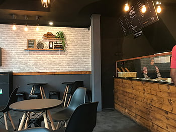 Black Pedestal Table, cozy modern cafe, stylish decor, Maldives cafe, interior design, cafe seating, brick wall decor, wooden counter, cafe ambiance, modern cafe interior, cafe furniture