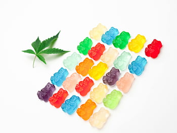 gummy bears, assorted colors, white background, cannabis leaf, vibrant gummies, colorful candies, sweet treats, edible treats, candy assortment, leaf decoration, gummy candies