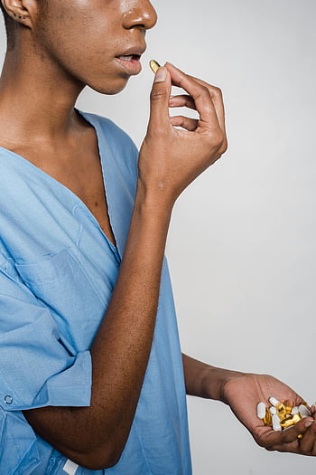 Black woman, blue patient gown, taking pills, healthcare, woman holding pills, medical care, health symbol, medication, patient care, healthcare symbol, pills