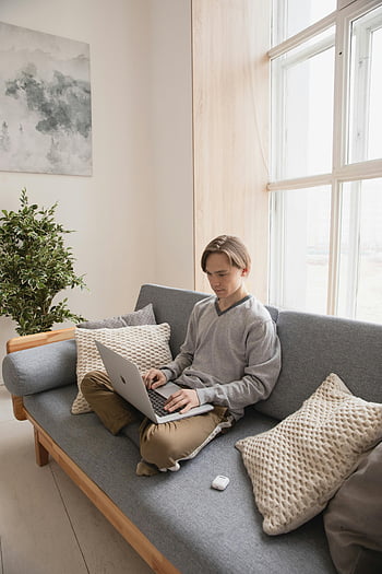mężczyzna siedzący na kanapie, laptop, Przytulna sofa, Jasny salon, młody człowiek, za pomocą laptopa, ustawienie wewnętrzne, Wygodne ustawienie, domowe biuro, Praca dorywcza, nowoczesny salon