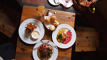 flat-lay photography, breakfast food, rustic wooden table, gourmet dishes, bread, drink, warm dining atmosphere, aerial view, dining table, food photography, meal presentation