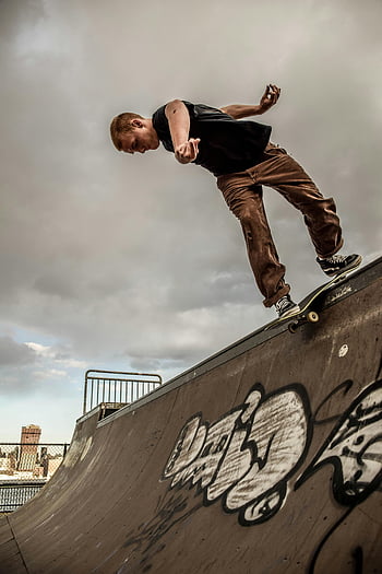 skateboarding, skateboardista, kousky, Rampa pokrytá graffiti, zatažené obloze, dynamický výstřel, Venkovní skatepark, městské sporty, akční fotografie, triky pro skateboarding, skateboard rampa
