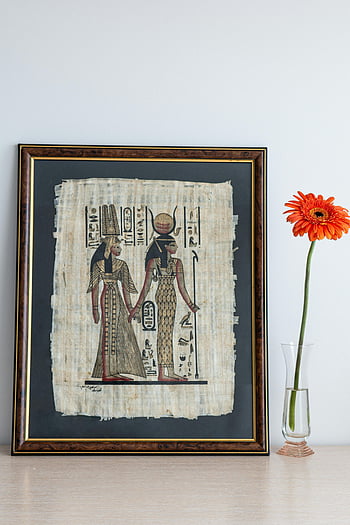 Ancient Egyptian artwork, papyrus, orange gerbera, glass vase, picture frame, table, Egyptian hieroglyphs, framed art, decorative flower, interior decor, wall art