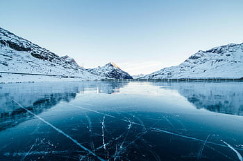 frozen lake, snow-covered mountains, winter landscape, serene scene, Switzerland, ice river photography, frozen water, mountain reflection, winter photography, alpine scenery, icy surface