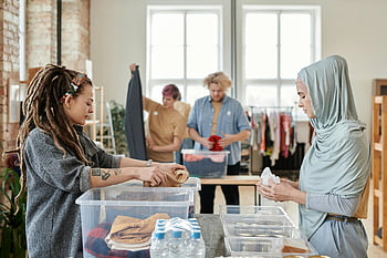 le persone che ordinano donazioni, Volontari che organizzano vestiti, volontariato, impostazione interna, vestiti donati, servizio alla comunità, donazione di abbigliamento, evento di beneficenza, volontari diversi, contenitori di plastica