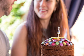 čokoládový dort, Barevné bonbóny, oslava narozenin, venkovní party, Shromažďování přátel, detailní fotografie, narozeninový dort, čokoládová poleva, Slavnostní příležitost, Atmosféra strany, Dekorace svíček