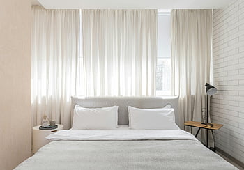 cozy bedroom, modern bedroom, neutral tones, soft lighting, minimalistic decor, white curtains, white bedding, bedside table, brick wall, cozy atmosphere, modern decor