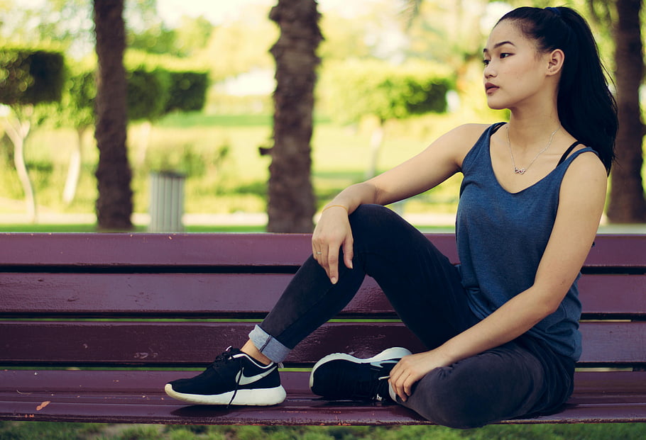 seduto sulla panchina, giovane donna, panchina del parco, la tranquillità, stile, all'aperto, Abbigliamento casual, scarpe da ginnastica, Posa rilassata, sfondo verde, palme