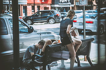 Žena sedí na lavičce, muž u ženy, ležérní městská ulice, Přátelé relaxační, mluvení u zaparkovaných aut, pouliční scény, městském prostředí, zaparkovaná auta, lavice, ležérní oblečení, pouliční život
