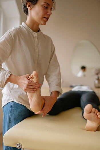 foot massage, therapist, indoor setting, health and wellness, massage therapy, comfortable environment, foot care, professional massage, relaxation, wellness imagery, indoor therapy