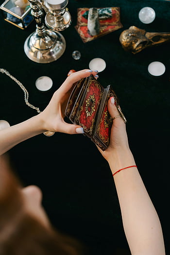 Wahrsager, Tarot-Karten, Karten mischen, Kerzen, Geheimnis, Divination, Tabelle, die Hände der Frau, rotes Armband, Kristallkugel, Schädel