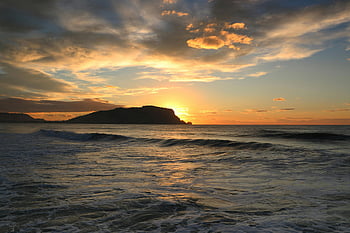 golden-hour photography, body of water, scenic ocean, sunset, waves, silhouetted island, colorful sky, ocean landscape, sunset photography, ocean sunset, island silhouette